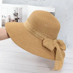 Détail d'un chapeau de paille kaki avec un grand nœud décoratif et une texture tressée
