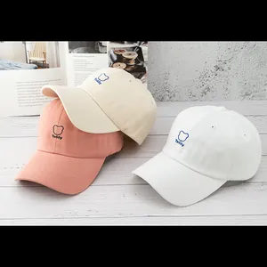Three cotton baseball caps with teddy bear embroidery on a wooden table setup