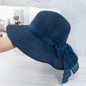 Détail du chapeau de paille bleu marine avec texture tissée et un grand nœud décoratif