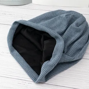 Blue waffle knit beanie with black lining on a warm wooden surface for winter wear