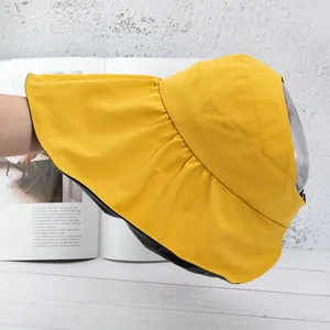 Detail of yellow sun hat with large brim, black lining and clear protective face shield