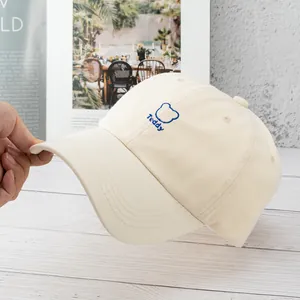 Detailed embroidery of a cartoon bear and Teddy text on a cream canvas baseball cap