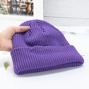 Detail of hand-held dark purple ribbed knit beanie with thick fold-over cuff for winter