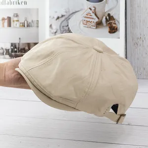 Detail view of beige newsboy hat showing woven cotton canvas texture and adjustable metal buckle