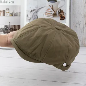 Detail of vintage khaki newsboy hat featuring textured fabric and adjustable metal buckle