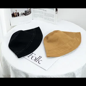 Détail des chapeaux bob en coton noir et jaune montrant les coutures fines sur le bord