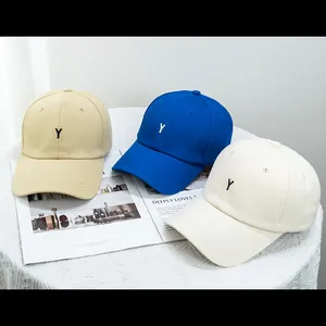 Trois casquettes de baseball en coton kaki, bleu et blanc avec broderie Y sur table