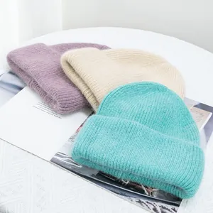 Detalle de gorros de punto suave en morado, beige y verde menta con textura de pelo de conejo