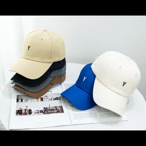 Détail de casquettes en coton avec broderie Y sur une nappe en dentelle blanche