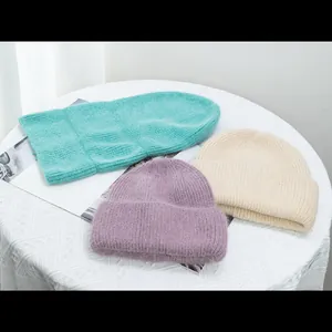 Detalle de tres gorros de punto de pelo de conejo en color menta, lila y beige crema suave