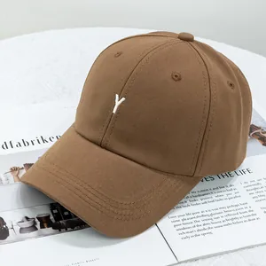 Détail de la broderie blanche de la lettre Y sur une casquette en coton sergé marron foncé