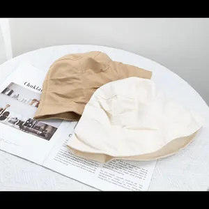Detailed close-up of khaki and beige pleated bucket hats on a vintage magazine base