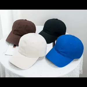 Close-up of four colored cotton baseball caps arranged on a white lace tablecloth