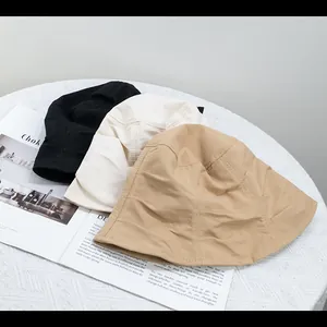 Foldable cotton bucket hats in black, cream, and khaki displayed on a magazine