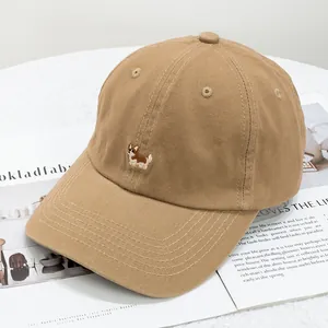 Detail of khaki cotton baseball cap with cute corgi dog embroidery on white fabric background