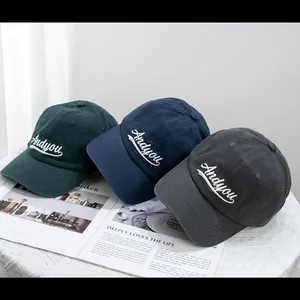 Close-up of cotton baseball caps in dark green and navy with letter embroidery detail