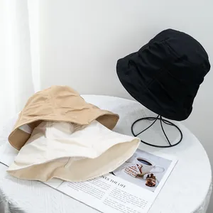 Three minimalist pleated bucket hats in black, khaki, and cream cotton fabric for women