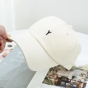 Détail d'une casquette en coton beige avec broderie Y noire et texture en sergé chic