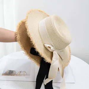 Détail d'un chapeau de paille à bord effiloché avec un élégant nœud en ruban