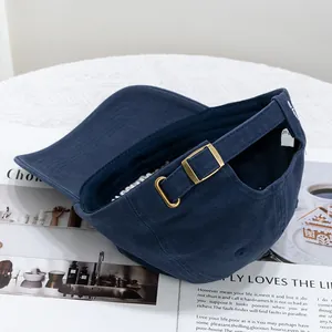 Detail of adjustable brass buckle and strap on navy blue cotton baseball cap