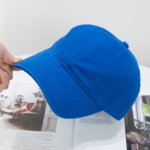 Detailed view of a hand holding a blue washed cotton baseball cap over a magazine
