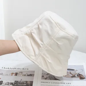 Detail view of cream bucket hat featuring pleated texture and decorative stitching