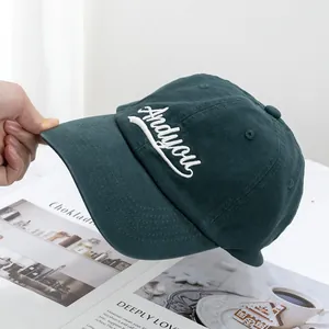 Close-up of white cursive 'Andyou' embroidery on dark green cotton canvas baseball cap