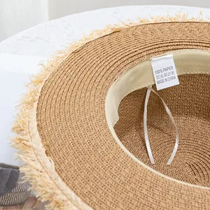 Détail du bord effiloché du chapeau de paille avec ruban intérieur et étiquette