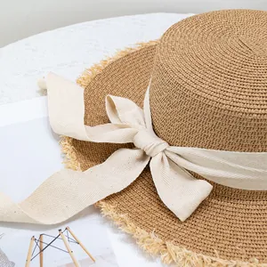 Chapeau de paille d'été à haut plat avec bords effilochés et nœud en ruban beige