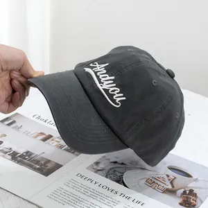Detailed close-up of dark grey baseball cap with white Andyou embroidery and distressed brim