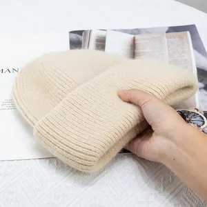 Textura detallada del gorro de punto grueso beige de pelo de conejo con borde doblado
