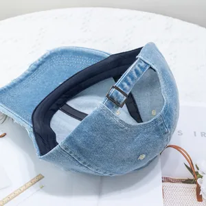 Detail of adjustable metal buckle and distressed denim texture on a light blue baseball cap