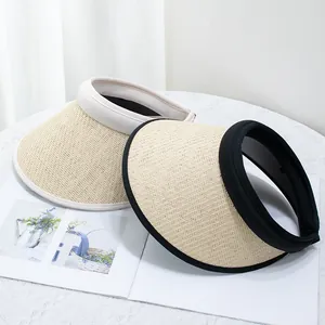 Detail of natural woven straw sun visor hats with black and beige trim edges