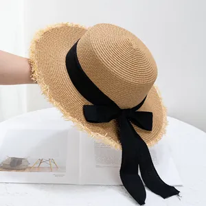 Détail d'un chapeau de paille à toit plat avec ruban noir et bord à franges