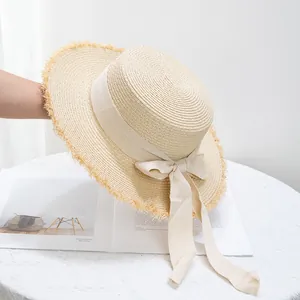 Gros plan détaillé d'un chapeau de paille beige avec bords effilochés et nœud élégant