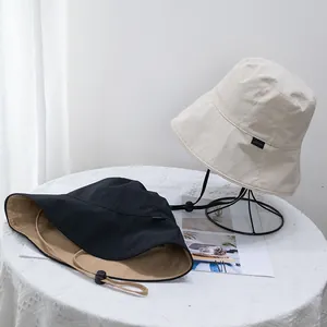 Close-up of dual-color sun hat with adjustable windproof cord and detailed side label