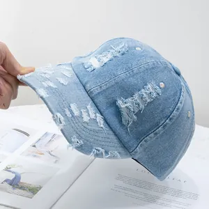 Close-up of light blue washed denim baseball cap with distressed details and holes