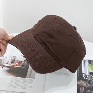 Detail view of washed dark brown cotton baseball cap fabric texture and reinforced brim stitching