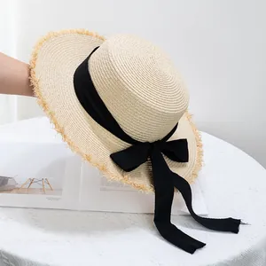 Détail d'un chapeau de paille à bord effiloché avec un ruban noir élégant