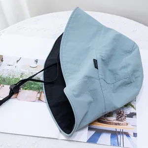 Detail view of light blue sun hat with black inner lining and adjustable windproof strap