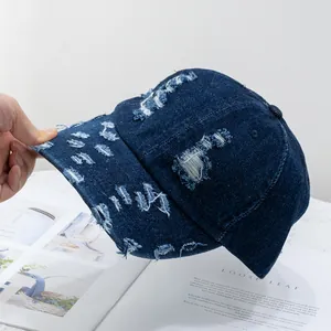 Macro detail of dark blue washed denim baseball cap featuring distressed ripped hole textures