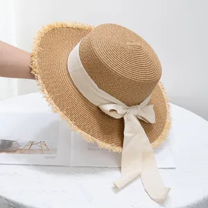 Détail d'un chapeau de paille aux bords effilochés avec un ruban et un nœud blanc élégant