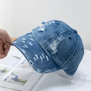 Detail of distressed blue denim baseball cap with vintage worn-out holes and raw edges
