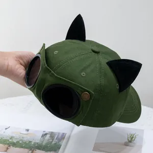 Detalle de gorra verde con orejas de gato de felpa negra y gafas de piloto decorativas
