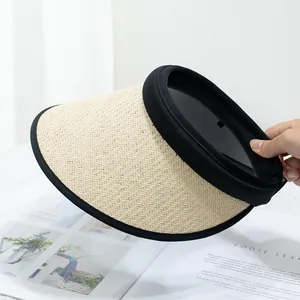 Detail of beige straw sun visor with black fabric trim held against a magazine background