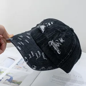 Detail of distressed ripped denim baseball cap showing vintage frayed edge texture