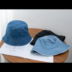Classic denim bucket hats in dark blue, light blue, and black on a rustic wooden table