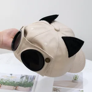 Detalle de gorra de béisbol beige con orejas de gato de felpa negra y gafas de sol