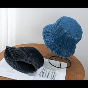 Detailed texture of denim bucket hats in dark blue and charcoal gray on a wooden table