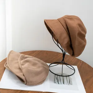 Détails de chapeaux cloches en daim vintage marron foncé et abricot sur une table